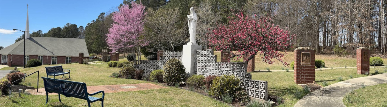 mary statue holding baby in garden with bench